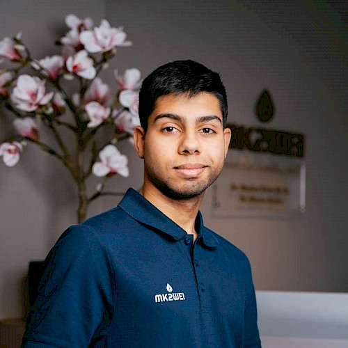 Bild zeigt eine lächelnden Mitarbeiter von MK2WEI im blauen Obertteil und schwarzen Haaren.